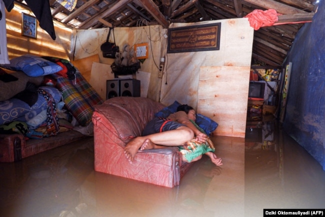 Seorang warga beristirahat di sofa rumahnya yang terendam banjir di Desa Sukajaya, Serang, 2 Maret 2022. (Foto: AFP/Dziki Oktomauliyadi)