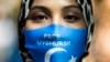 资料照：一名在中国驻德国大使馆前抗议中国外长王毅访德的女子戴着写有“自由维吾尔人”字样的口罩。（2020年9月1日）