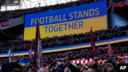 FILE - A video screen displays the Ukrainian flag, during the English League Cup final soccer match between Chelsea and Liverpool at Wembley stadium in London, Feb. 27, 2022.
