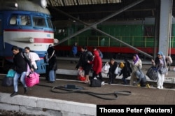Las personas que huyen de la invasión rusa de Ucrania, cruzan las vías del tren para llegar a un tren que sale hacia Polonia, en la estación de tren de Lviv, Ucrania, el 28 de febrero de 2022. REUTERS/Thomas Peter
