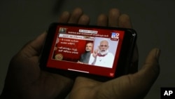 A man in Hyderabad, India watches on his mobile phone Prime Minister Narendra Modi address the nation in a televised speech about COVID-19 situation, April 14, 2020, extending nationwide lockdown through May 3