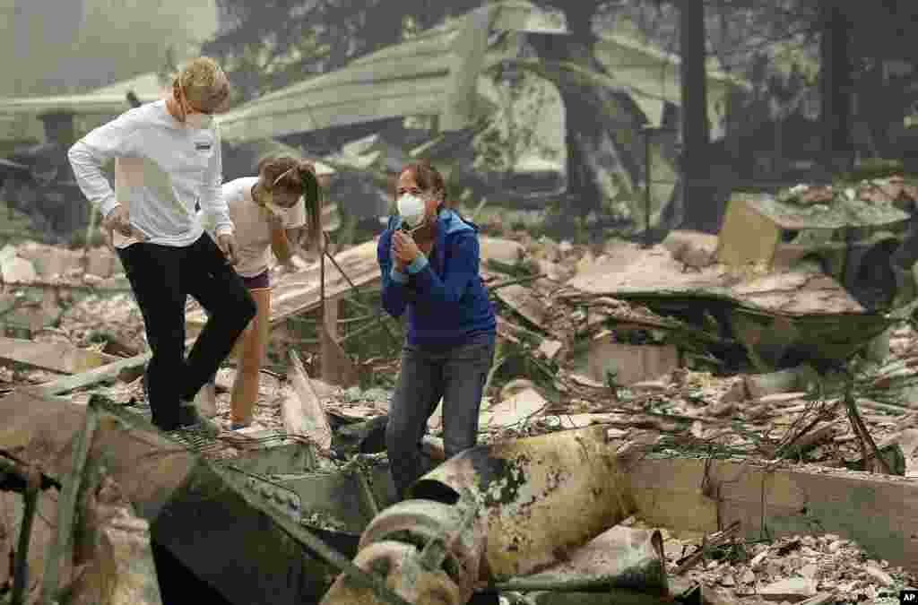 Mary Caughey, center in blue, reacts with her son Harrison, left, after finding her wedding ring in debris at her home destroyed by fires in Kenwood, California.