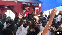 Migrants celebrate aboard the Ocean Viking rescue ship, jointly operated by French NGOs SOS Mediterranee and Medecins sans Frontieres (Doctors without Borders), Aug. 23, 2019, as six EU countries agreed to take them in after 14 days stranded at sea.