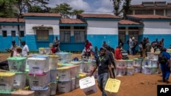 An electoral worker carries ballot boxes at a collection and tallying center in Nairobi, Kenya Wednesday, Aug. 10, 2022. 