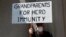FILE - A demonstrator holds a sign reading "Grandparents for Herd Immunity" as protestors rally against COVID-19 restrictions outside the Pennsylvania State Capitol Building in Harrisburg, Pennsylvania, U.S., May 15, 2020.