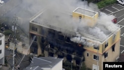 FILE - An aerial view shows firefighters battling fires at the site where a man started a fire after spraying a liquid at a three-story studio of Kyoto Animation Co. in Kyoto, western Japan, in this photo taken by Kyodo, July 18, 2019. 