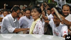 Burma pro-democracy leader Aung San Suu Kyi leaves the National League for Democracy head office after a news conference to mark the first anniversary of her release from house arrest, in Rangoon, November 14, 2011.