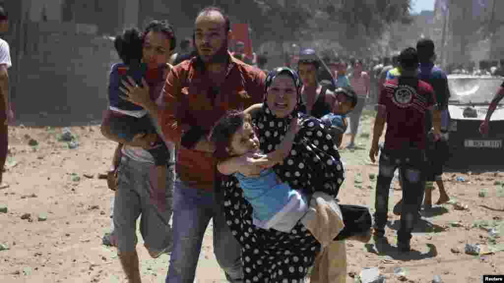 A Palestinian woman runs carrying a girl following what police said was an Israeli air strike on a house in Gaza city July 9, 2014.