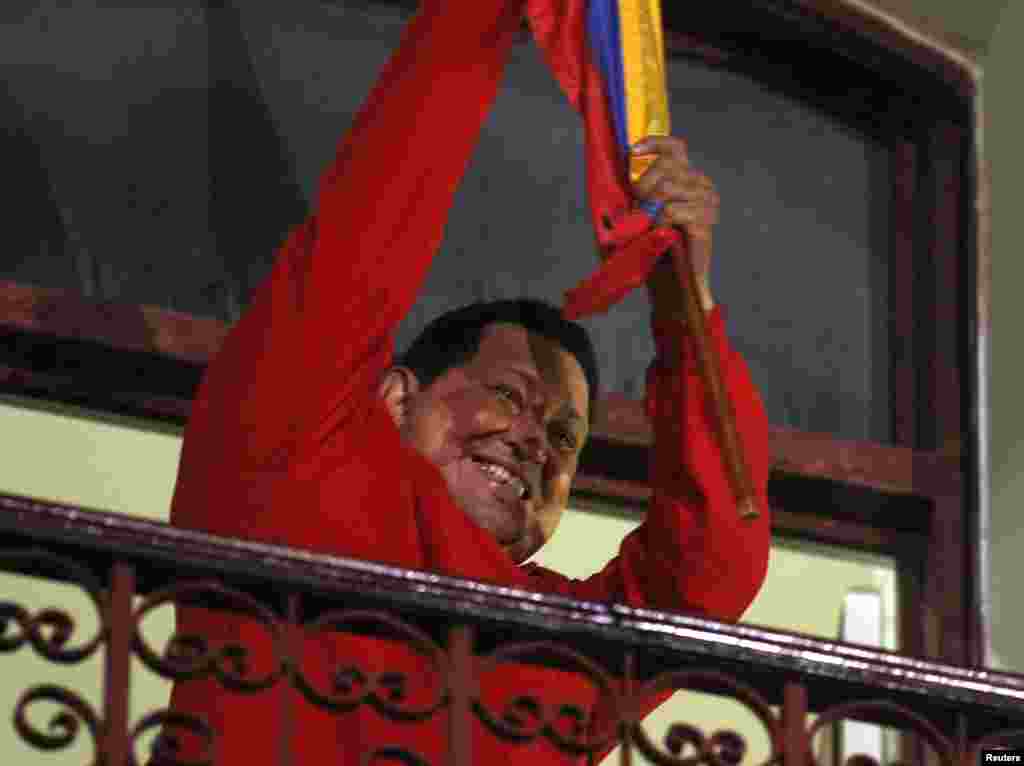 ປະທານາທິບໍດີ Venezuela ທ່ານ Hugo Chavez ຈັບທຸງຊາດ ຂະນະທີ່ສະຫລອງໄຊຊະນະ ຢູ່ລະບຽງ ປາສາດ Miraflores ຫລືທໍານຽບປະທານາທິບໍດີ ທີ່ນະຄອນຫລວງ Caracas, ວັນທີ 7 ຕຸລາ 2012.