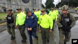 FILE - This undated photo released by Colombia's National Police shows officers escorting a man whom police identified as Ecuadorean drug trafficker Washington Edison Prado after his April 2017 arrest on an indictment by a Florida federal court. Colombia’s chief prosecutor’s office said Feb. 24. 2018, that it had extradited Prado to the United States.