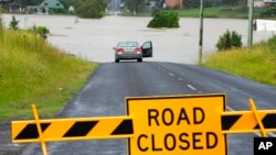 A car is parked near a flooded road at Windsor on the outskirts of Sydney, March 3, 2022.