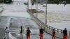 Tim Penanggulangan Keadaan Darurat Negara berdiri di dekat pintu masuk jembatan Windsor yang terendam banjir di pinggiran Sydney, Australia, Kamis, 3 Maret 2022. (Foto AP/Rick Rycroft)