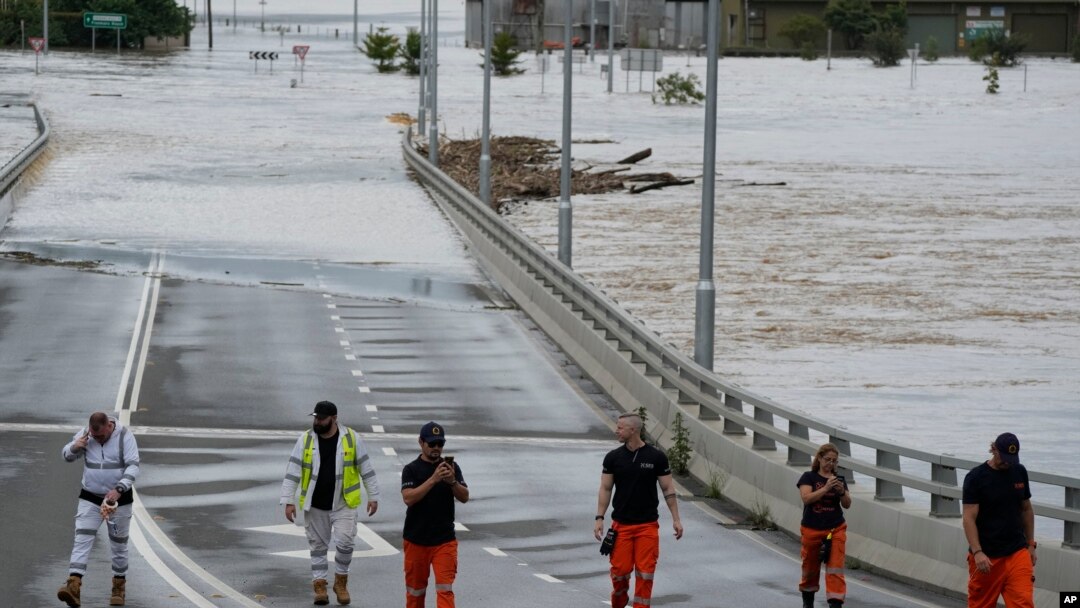 Tim Penanggulangan Keadaan Darurat Negara berdiri di dekat pintu masuk jembatan Windsor yang terendam banjir di pinggiran Sydney, Australia, Kamis, 3 Maret 2022. (Foto AP/Rick Rycroft)