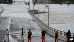 Tim Penanggulangan Keadaan Darurat Negara berdiri di dekat pintu masuk jembatan Windsor yang terendam banjir di pinggiran Sydney, Australia, Kamis, 3 Maret 2022. (Foto AP/Rick Rycroft)