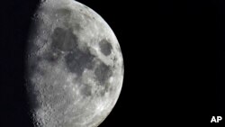 FILE - Impact craters cover the surface of the moon, seen from Berlin, Germany, Jan. 11, 2022. The moon is in line to be hit March 4 hit by 3 tons of space junk, a leftover rocket part.