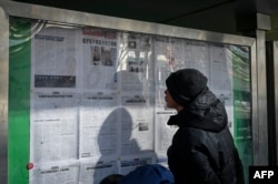 FILE - A man reads the Chinese state-run newspaper with coverage of the conflict between Russia and Ukraine, on a street in Beijing, Feb. 24, 2022.