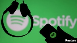 FILE: A smartphone and a headset are seen in front of a screen projection of Spotify logo, in this picture illustration taken April 1, 2018. 