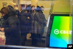 People stand in line to withdraw money from an ATM in Sberbank in St. Petersburg, Russia, Feb. 25, 2022.