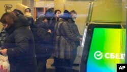 FILE - People stand in line to withdraw money from an ATM in Sberbank in St. Petersburg, Russia, Feb. 25, 2022.