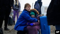 A woman holds a child at a border crossing, up as refugees flee a Russian invasion, in Medyka, Poland, March 3, 2022. 