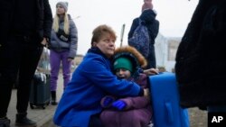 A woman holds a child at a border crossing, up as refugees flee a Russian invasion, in Medyka, Poland, March 3, 2022.