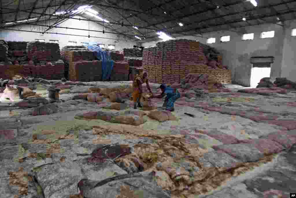 Para perempuan membersihkan biji-bijian yang rusak karena banjir di gudang milik pemerintah di Jagannathpur, distrik Ganjam di negara bagian Orissa, India (26/10). (AP/New York Stock Exchange)