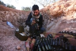 A Turkish-backed Syrian fighter loads ammunition at a front line near the town of Saraqeb in Idlib province, Syria, Feb. 26, 2020.