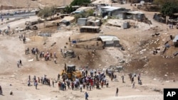 Palestinians gather around a bulldozer in Khan al-Ahmar, Wednesday, July 4, 2018. Israeli police scuffled with activists at a West Bank Bedouin community ahead of its planned demolition.