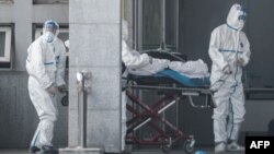 Personal médico transporta a un paciente hacia un hospital donde tratan a pacientes con un misterioso virus similar al SARS en Wuhan, China, el 18 de enero de 2020.