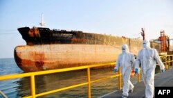This photo taken on Nov. 16, 2020 shows Chinese immigration inspection officers in protective suits walking past an oil tanker ship at the port in Qingdao, in China's eastern Shandong province. 