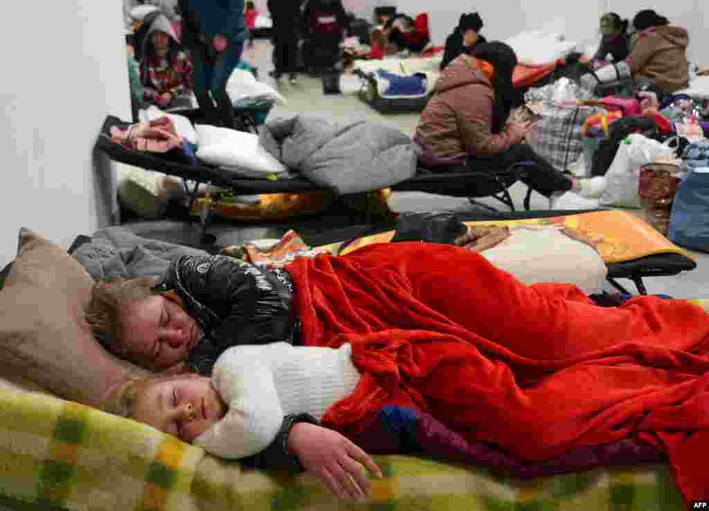 Refugiados de Ucrania descansan mientras esperan el transporte a otros destinos, el 4 de marzo de 2022 en un centro comercial vacío en Przemysl, Polonia.