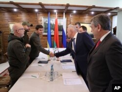 Ukrainian and Russian delegations greet each other prior to the Russian-Ukrainian talks in the Belavezhskaya Pushcha National Park, close to the Polish-Belarusian border, northward from Brest, Belarus, March 3, 2022.