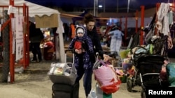 Seorang perempuan menggendong seorang anak di perbatasan Ukraina-Slovakia menyusul invasi Rusia ke Ukraina, di Vysne Nemecke, Slovakia, 4 Maret 2022. (Foto: REUTERS/Lukasz Glowala)