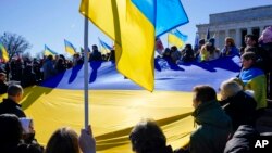 FILE - People hold a large Ukrainian national flag as they gather for a vigil in solidarity with Ukraine, at the Lincoln Memorial in Washington, Feb. 20, 2022.