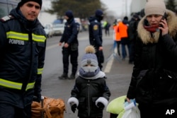 A firefighter helps refugees fleeing the conflict from neighbouring Ukraine at the Romanian-Ukrainian border, in Siret, Romania, March 4, 2022.