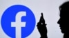 FILE - In this photo illustration, a person looks at a smartphone with a Facebook App logo displayed on the background, on Aug. 17, 2021, in Arlington, Virginia. 