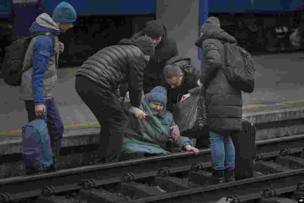 Una mujer recibe ayuda después de caer en las vías tratando de llegar a un tren con destino a Lviv, en Kiev, Ucrania, el jueves 3 de marzo de 2022.&nbsp;