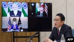 This picture taken March 3, 2022, shows Japanese Prime Minister Fumio Kishida attending the Quadrilateral Security Dialogue online meeting in Tokyo, with (on screen) Indian Prime Minister Narendra Modi, U.S. President Joe Biden and Australia's Prime Minister Scott Morrison. 