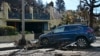 A stranded car sits next to a burned building near the Palisades Fire zone in the aftermath of a storm in the Pacific Palisades neighborhood of Los Angeles, California, Feb. 14, 2025.