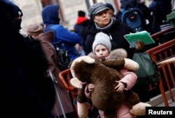 A child holds a plush toy as a Ukrainian train transporting hundreds of people fleeing from the Russian invasion of Ukraine arrives at the train station in Przemysl, Poland, March 3, 2022.