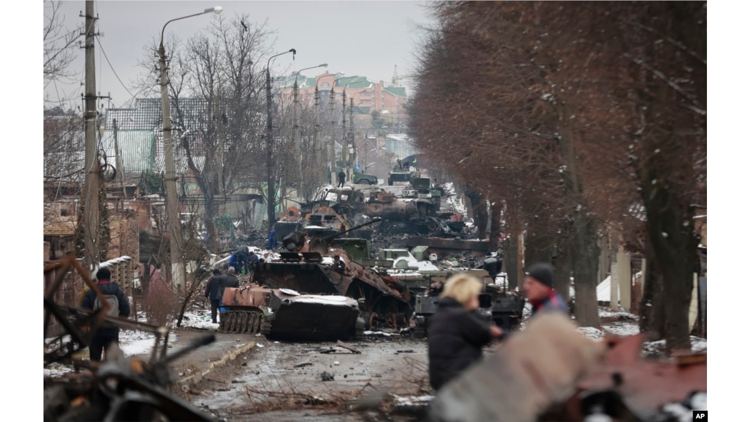 Orang-orang melihat sisa-sisa kendaraan militer Rusia yang hancur di jalan di kota Bucha, dekat Ibu Kota Kyiv, Ukraina, Selasa, 1 Maret 2022. (Foto: AP)