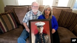 FILE - Joey and Paula Reed pose for a photo with a portrait of their son Marine veteran and Russian prisoner Trevor Reed at their home in Fort Worth, Texas, Feb. 15, 2022.