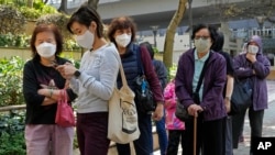 People wearing protective face masks line up to receive a dose of China's Sinovac COVID-19 coronavirus vaccine at a community vaccination center in Hong Kong, March 3, 2022.
