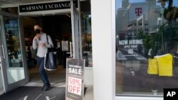 FILE - Sale and hiring signs are displayed at a Armani store, Jan. 21, 2022, in Miami Beach, Fla. 