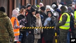 A woman holds her dog as she stands with other displaced Ukrainians on the train platform after arriving from Ukraine at the station in Przemysl, Poland, March 3, 2022.