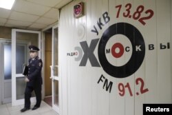 FILE - An Interior Ministry officer walks inside the office of Russian radio station Ekho Moskvy, in Moscow, Russia, Oct. 23, 2017.