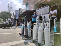 Indonesians, fortunate to have their own oxygen tanks, line up at an oxygen supply station in Tebet, Jakarta, July 4, 2021, after a hospital ran out of supplemental oxygen, asking patients' families to bring their own. (Indra Yoga/VOA-Jakarta)