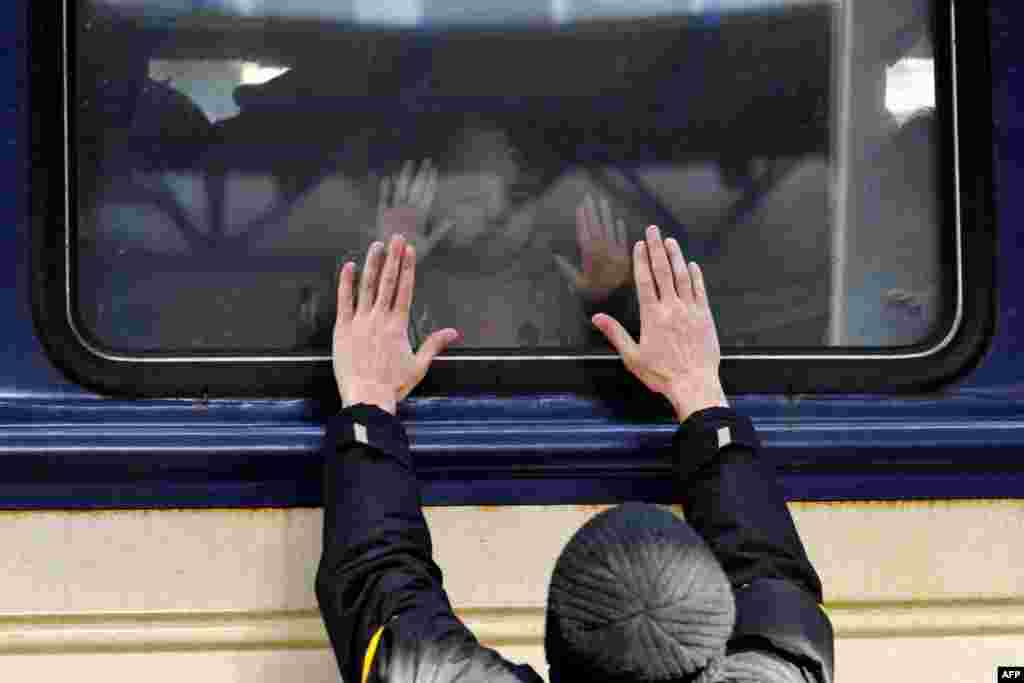 A man makes a movement with his bands in front of an evacuation train at Kyiv&#39;s central train station in Ukraine.