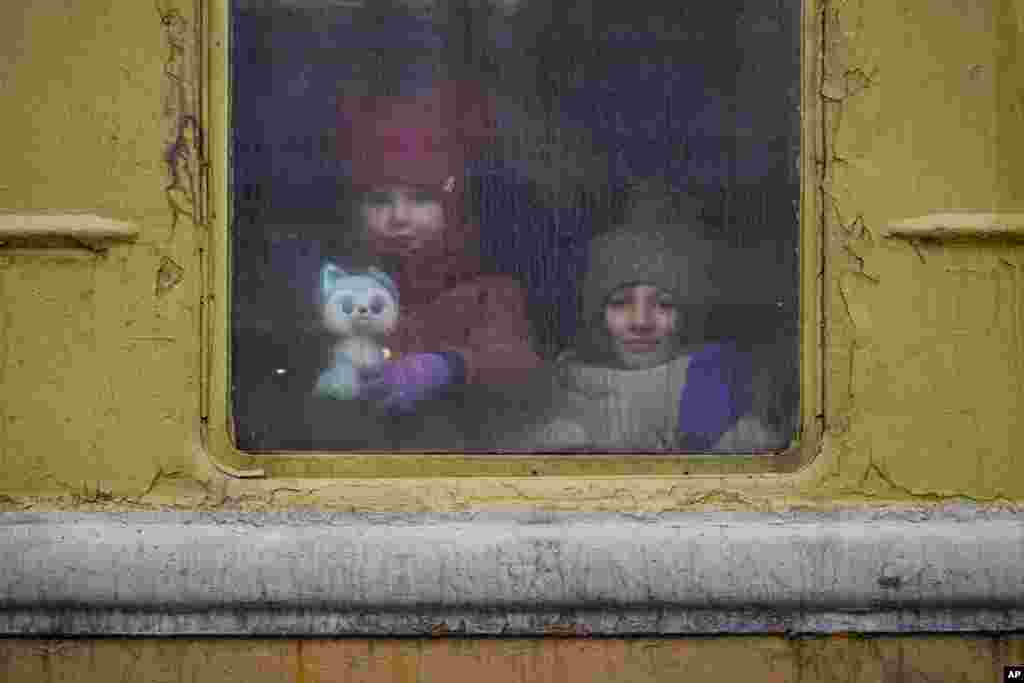 Los niños miran por la ventana de un tren sin calefacción con destino a Lviv, en Kiev, Ucrania, el jueves 3 de marzo de 2022.