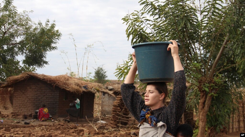 FILE - Cameron Beach, carries a carries a bucket of water on her head collected from a communal borehole in Dedza, near Lilongwe, Malawi, on July 23, 2021. The Peace Corps says it'll start sending volunteers overseas again in mid-March.